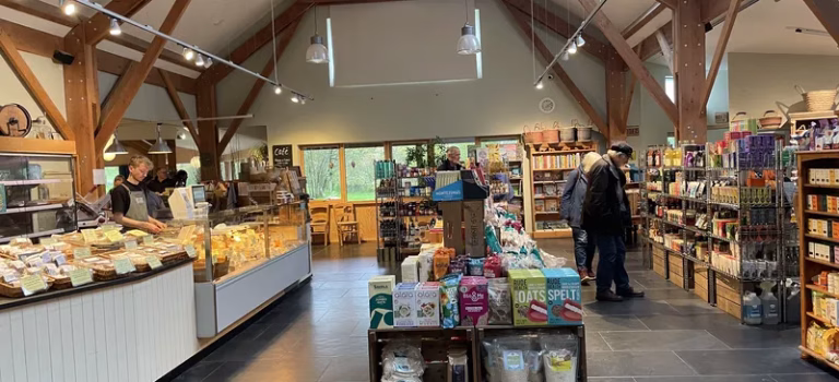 Loch Arthur Farm Shop and Café The spacious oak timber-framed interior of Loch Arthur Farm Shop and Cafe showing shelves of local artisanal food and produce.
