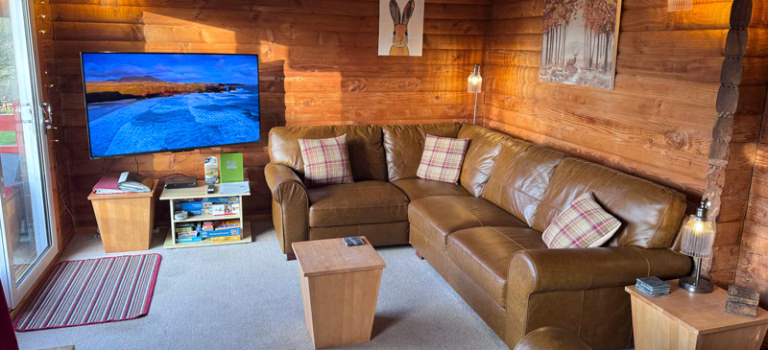 Cosy wooden lounge with leather sofas and large TV inside Serenity 22 Barend holiday lodge near Sandyhills in Dumfries & Galloway