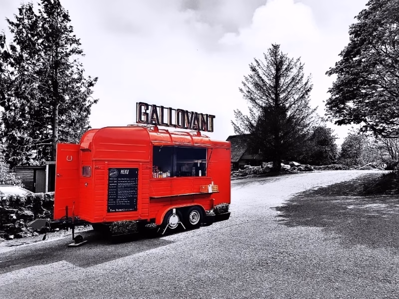 A vibrant red vintage horsebox converted into the 'Gallovant' food trailer, parked outside the courtyard at Barend with a menu displayed on the side.