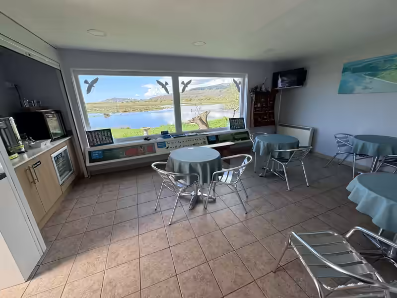 The indoor seating area and large wildlife viewing window inside the RSPB Mersehead visitor centre.